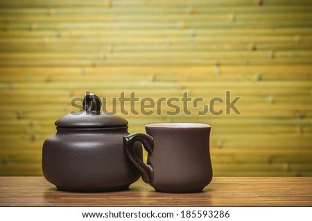 Cup and clay bowl on green bamboo background