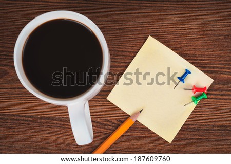 Cup of coffee, pencil, sticker and drawing pins on the office desk