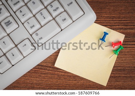 Keyboard, sticker and drawing pins on the office desk