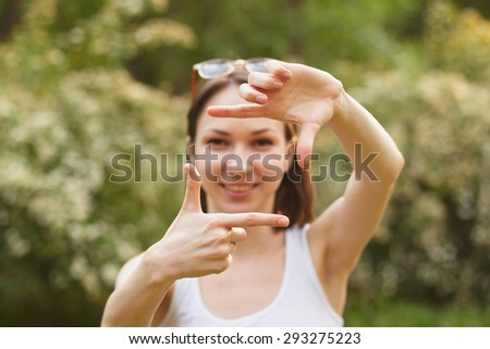 Pretty girl in white t-shirt and sunglasses, making frame with hands, taking picture with imaginary camera, focus on hands