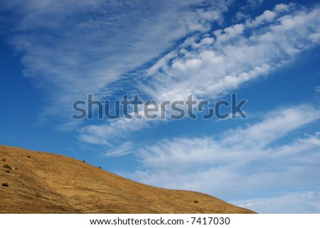 A country hillside with a big blue sky and clouds
