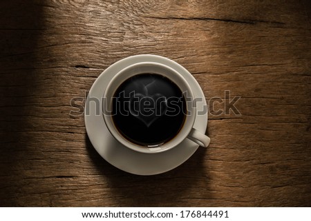 Coffee with heart shaped smoke and morning light. Shines through on old wood background.
