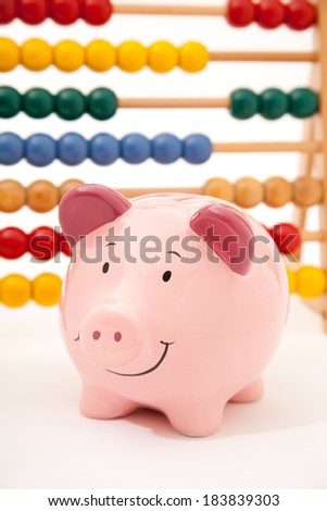 Smiling pink piggy bank standing in front of an abacus.