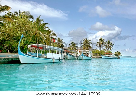 4 boats in a tropical resort island in Maldives. on one boat the maldivian flag is visible.