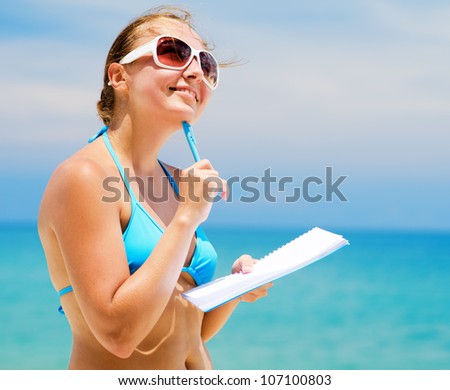 Young woman with notebook on a beach.