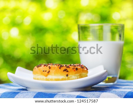 Fresh donut and glass of milk on nature background.
