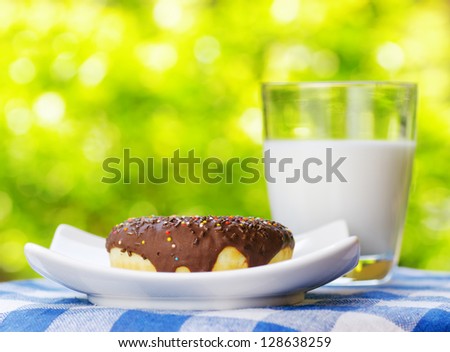 Fresh donut and glass of milk on nature background.