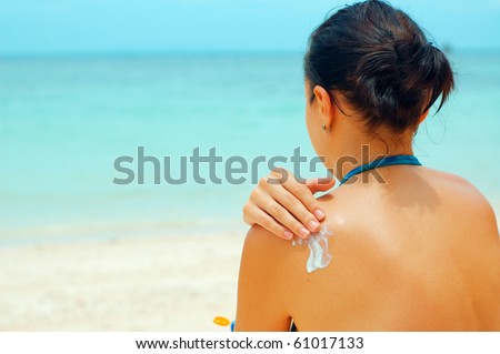 Woman applying sun lotion on the beach.