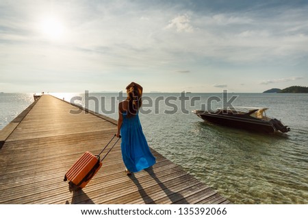 Young woman with suitcase on the pier.