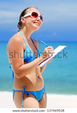 Young woman with notebook on a beach.