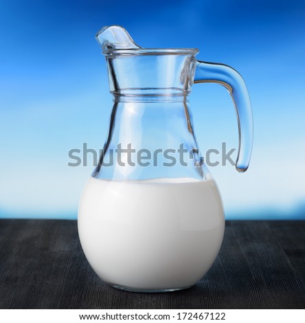 Jug of milk on sky background. Half full pitcher.