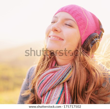 Young woman enjoying a music in the fall season. Autumn outdoor portrait.
