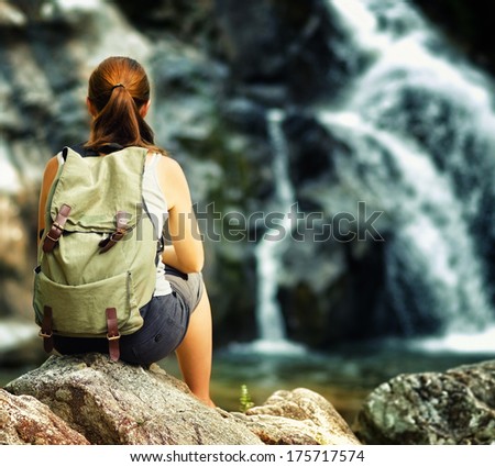 Female hiker looking at waterfall.