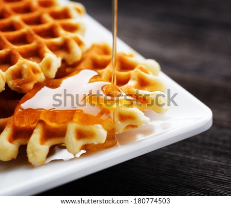Honey pouring on a fresh waffles.