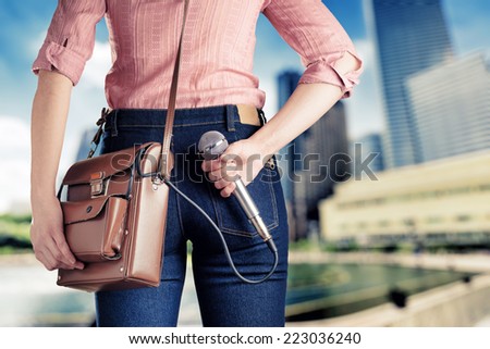 Female journalist with microphone. Retro style jeans and bag.