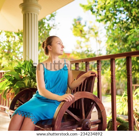 Young woman in blue dress relaxing in house terrace. Outdoor portrait.