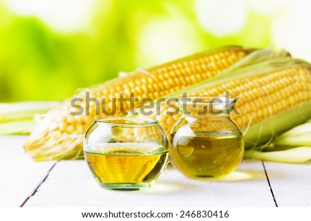 Corn oil and corn cobs on a garden table.