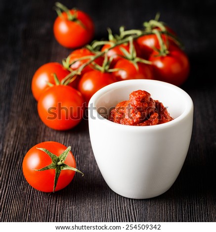 Ripe tomatoes and tomato paste on a wooden cooking table. Ketchup making. Eco food rich in minerals and vitamins. Product of organic farming