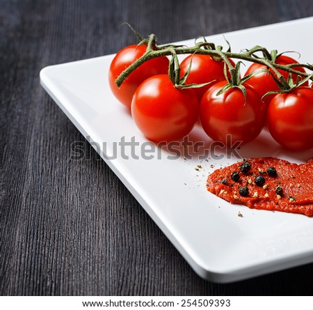 Ripe tomatoes and tomato paste in a white plate on a wooden table. Ketchup making. Eco food rich in minerals and vitamins. Product of organic farming.