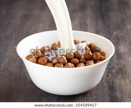 Fresh milk and chocolate cereal in a white bowl on a wooden table. Organic healthy food rich in minerals and vitamins. Eco food for breakfast.