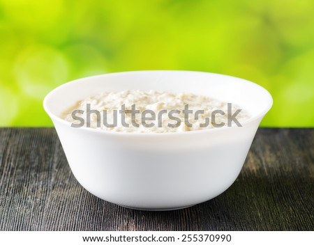 Bowl of oat porridge on nature background. Organic healthy food rich in minerals and vitamins. Eco food for breakfast.