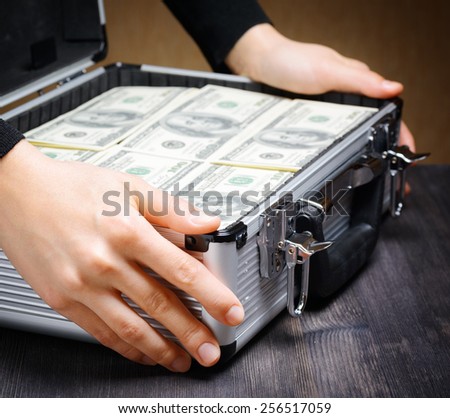 Storage and protection of cash and valuable items. Banking concept. Business man opens an aluminum briefcase full of stacks of hundred-dollar bills before a deal. Money in safe hands.