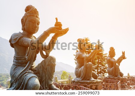 Buddhist statues praising and making offerings to the Tian Tan Buddha (the Big Buddha) in sunlight at Lantau Island, in Hong Kong. Hong Kong is popular tourist destination of Asia.