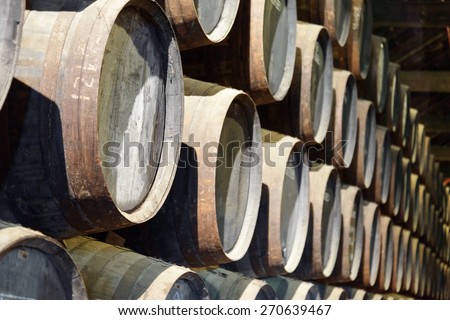 Numerous oak barrels stacked in the old cellar with aging Port wine from the vineyards Douro Valley in Portugal. Product of organic farming.