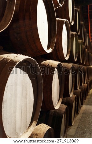 Side view of oak barrels stacked in the old cellar with aging Port wine from the vineyards Douro Valley in Portugal. Product of organic farming.