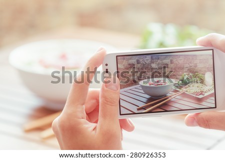 Closeup view of lifeview process on a smartphone for taking a picture of Pho Bo in street cafe in Vietnam. The Pho Bo is a traditional Vietnamese beef noodle soup. Popular healthy street food.