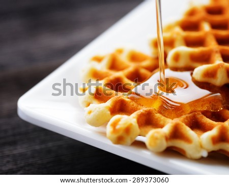 Honey pouring on a fresh waffles. Organic healthy food rich in minerals and vitamins. Eco food for breakfast. Trendy sweet confections.
