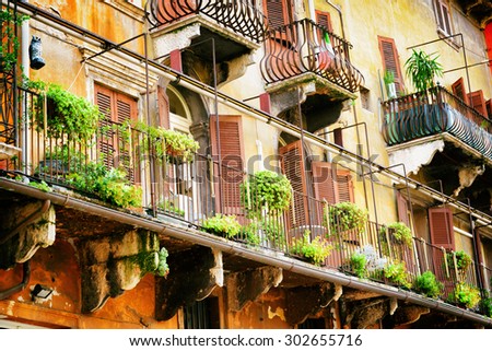 Scenic balconies of old house decorated with flowers in pots, Verona, Italy. Verona is a popular tourist destination of Europe.