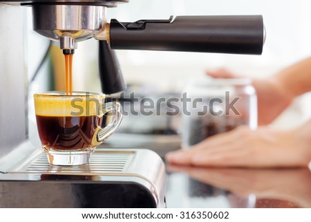 Espresso coffee machine in kitchen. Jets of hot invigorating coffee pouring into cup.