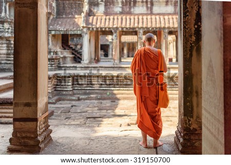 Buddhist monk exploring ancient courtyards of temple complex Angkor Wat in Siem Reap, Cambodia. Amazing Angkor Wat is a popular destination of tourists and pilgrims.