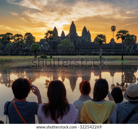 Asian tourists taking picture of ancient temple Angkor Wat at sunrise. Siem Reap, Cambodia. Angkor Wat is a popular tourist attraction. Focus point on the temple.