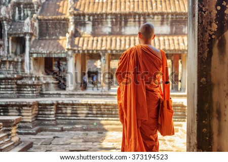 Buddhist monk looking at courtyard of ancient temple complex Angkor Wat in Siem Reap, Cambodia. Amazing Angkor Wat is a popular destination of tourists and pilgrims.