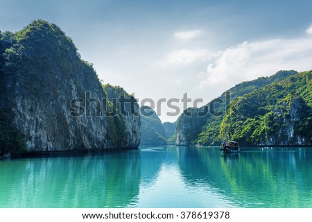 Beautiful view of lagoon in the Halong Bay (Descending Dragon Bay) at the Gulf of Tonkin of the South China Sea, Vietnam. Landscape formed by karst towers-isles on blue sky background.