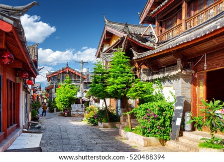 Scenic street in the Old Town of Lijiang, Yunnan province, China. Wooden facades of traditional Chinese houses. The Old Town of Lijiang is a popular tourist destination of Asia.