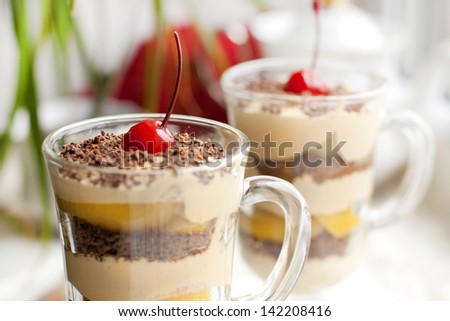 Dessert with canned peaches, cream cheese and chocolate, decorated with cocktail cherry