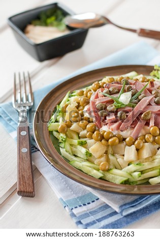 Polish salad with potatoes, ham, cucumber, green peas, capers and mayonnaise