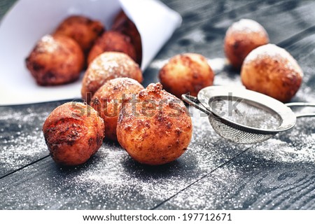 Fresh fried donuts with powdered sugar on black wooden table