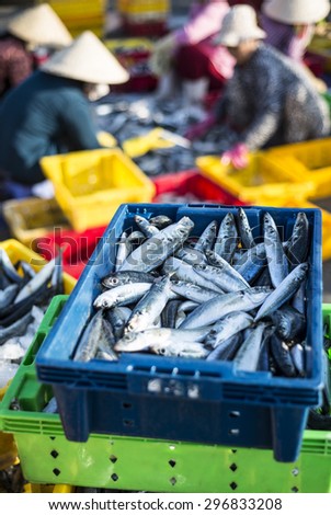 Fresh fishes on basket for sale in a beach market with the background of women wear conical hat