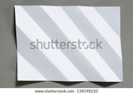 Full page white folded and wrinkled on gray background with shadow