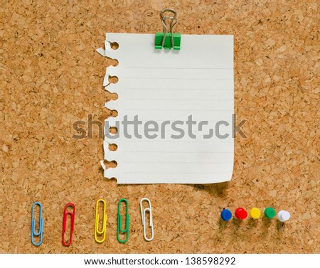 white note paper with paperclip on cork board