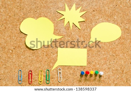 yellow note paper with paperclip on cork board
