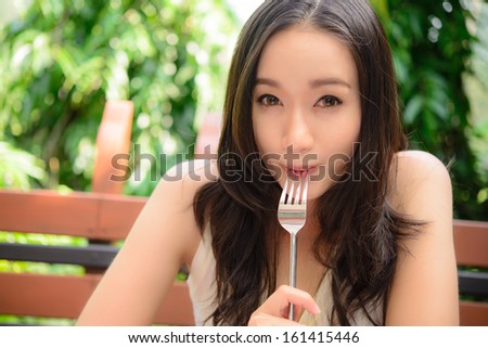 Portrait of young smiling woman with fork in her mouth