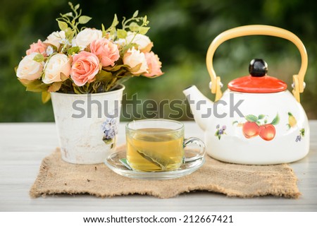 cup of tea in garden with pot and flower