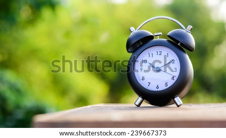 green bokeh background with retro alarm clock on wood table