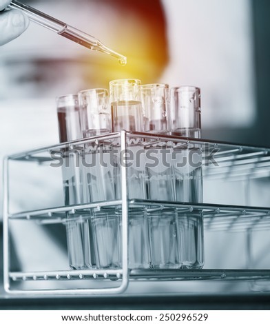 Glass laboratory chemical test tubes with liquid.Man wears protective goggles ; lighting effect vintage style