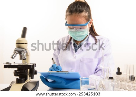 scientist writing report with equipment and science experiments